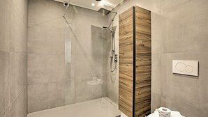 A modern bathroom with a glass-enclosed shower, a wooden vanity, and a toilet with a towel and toilet paper. - Porto Letizia P7, Porlezza, Italy (Porlezza)