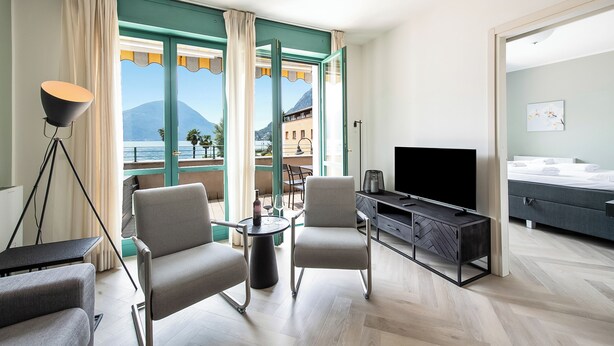 Quarto de hotel moderno com uma janela grande, televisão, cama e área de estar.