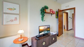A living room with a TV, a lamp, and a plant on a shelf. - Porto Letizia P12, Porlezza, Italy (Porlezza)