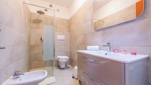 Ein modernes Badezimmer mit Duschkabine aus Glas, einem weißen Waschbecken und einem Waschtisch mit Schubladen.