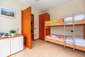 Une chambre avec un lit superposé, un bureau agrémenté d’une plante et une armoire.
