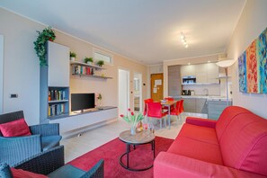 A modern living room with a red sofa, a grey sofa, and a dining area with red chairs.