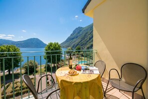 A balcony with a table, chairs, a bottle, glasses, and a plate of snacks.