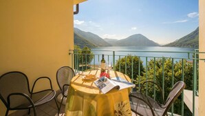 A balcony with a table set for two, overlooking a lake with mountains in the background. - Porto Letizia T11, Porlezza, Italy (Porlezza)
