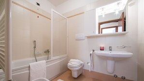 A bathroom with a bathtub, toilet, sink, and mirror. - Porto Letizia T11, Porlezza, Italy (Porlezza)