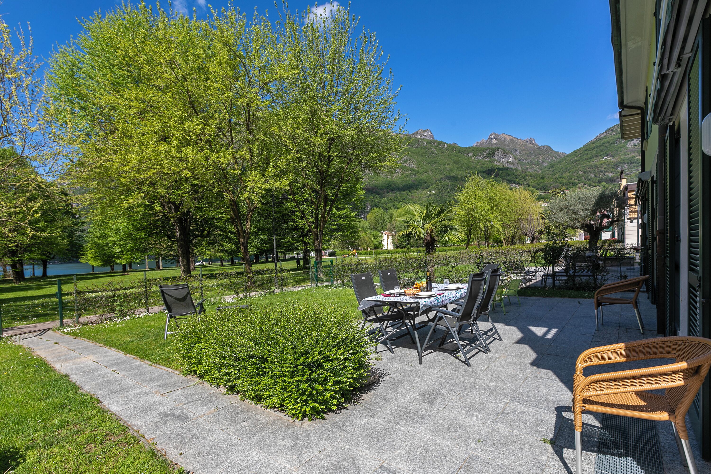 Une terrasse extérieure avec une table et des chaises, entourée de verdure et offrant une vue sur les montagnes.