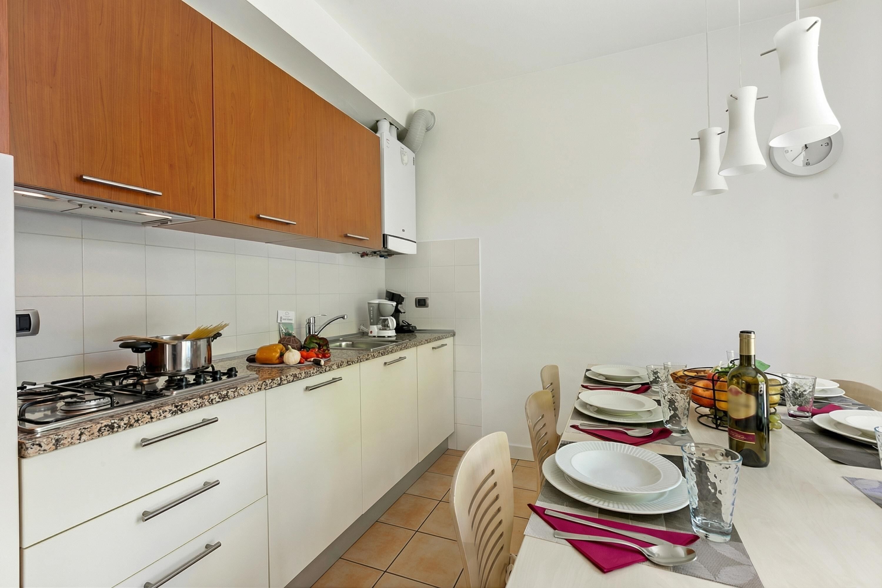 A modern kitchen with white cabinets, a gas stove, and a dining area set for a meal.