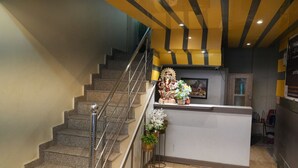 Un vestíbulo de hotel con una escalera, una mesa de recepción y una estatua.