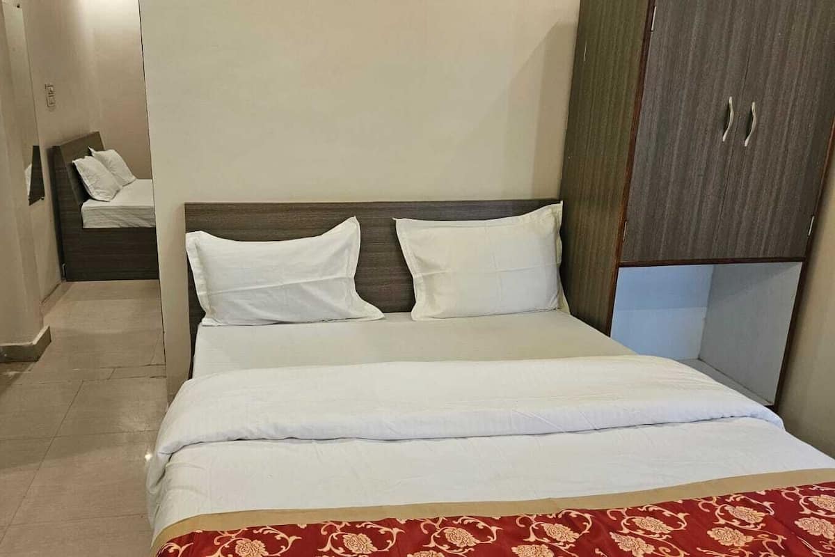 Una habitación de hotel con una cama, un armario y un pequeño rincón de descanso con una mesa y sillas.