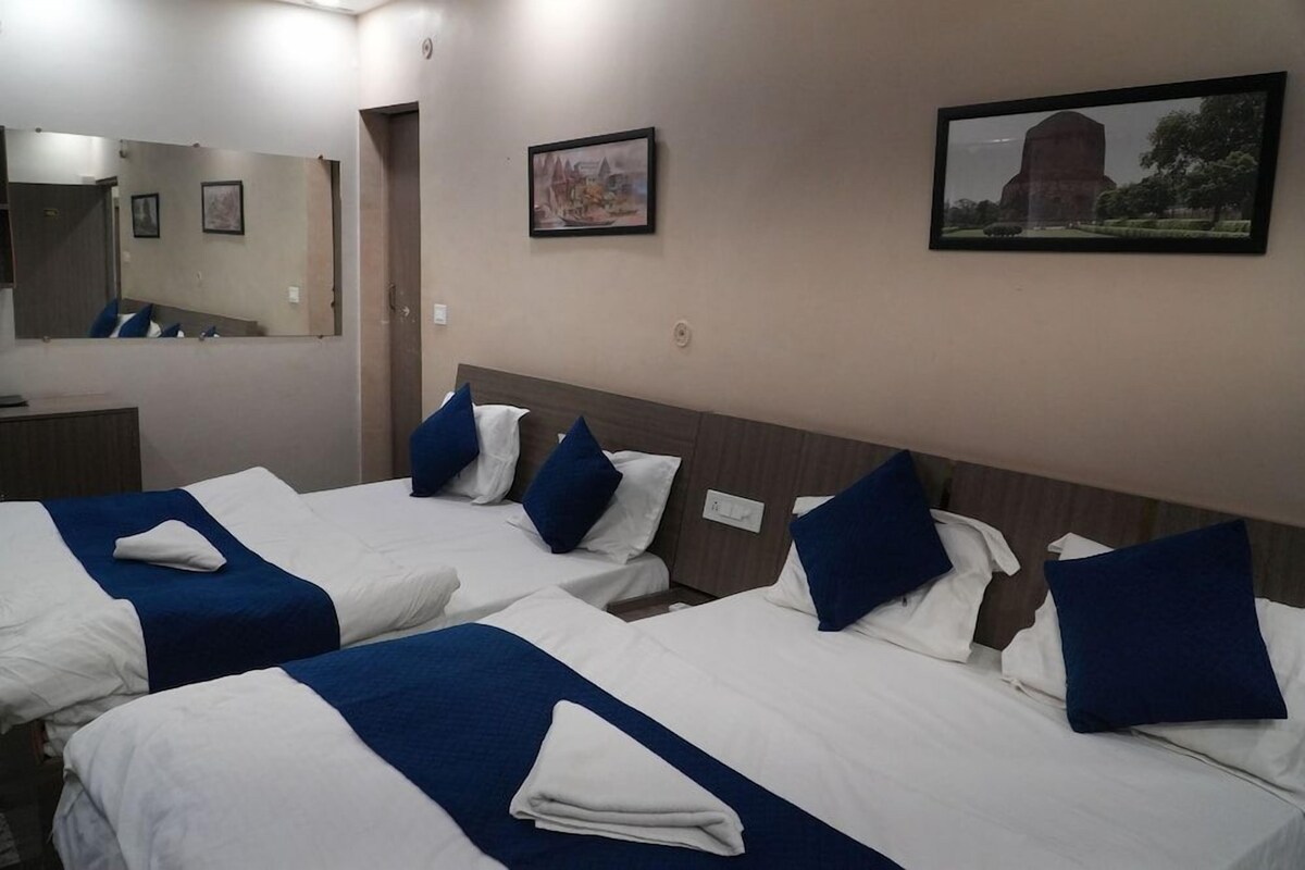 A hotel room with two beds, each with white and blue bedding, a large mirror, and two framed pictures on the wall.