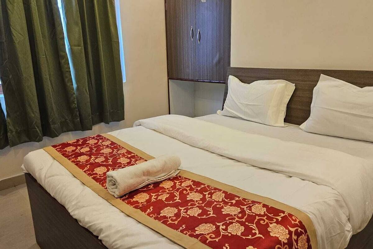 Una habitación de hotel con una cama, un armario y una ventana con cortinas.