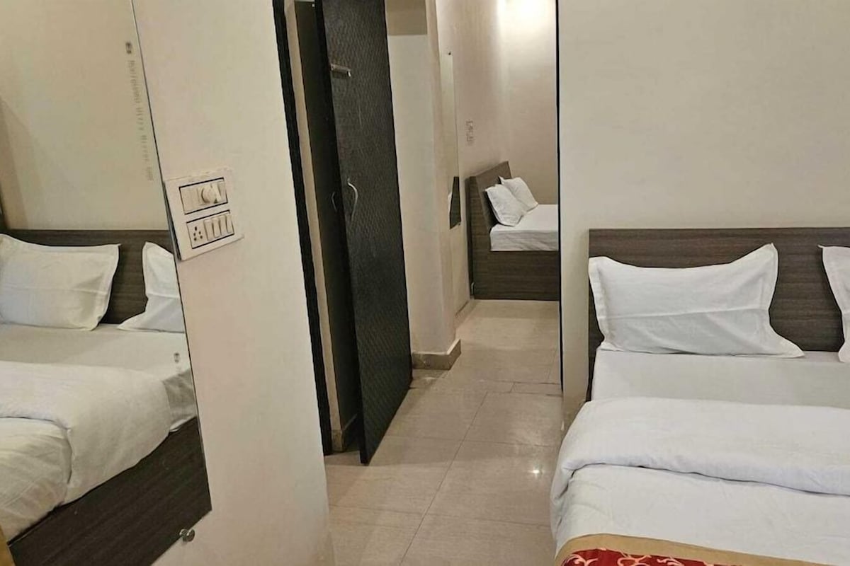 A hotel room with two beds, a door, and a wall socket.
