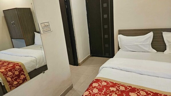 A hotel room with two beds, a wardrobe, and a door with a lock.