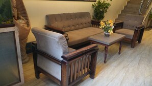 Una sala de estar con un sofá marrón, dos sillones y una mesa de centro de madera.