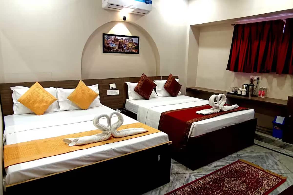 Habitación de hotel con dos camas, cada una con una colcha roja y blanca, y una cortina roja en la ventana.