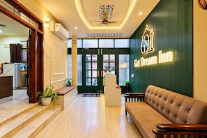 A hotel lobby with a reception desk, a sofa, and a staircase leading to another area. - Hotel Get Dreams Inn, Varanasi (Varanasi)