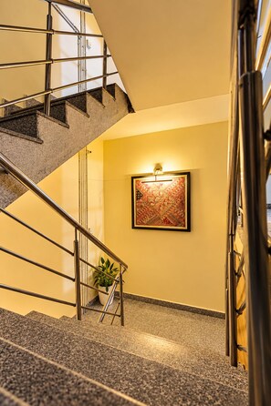 A staircase with metal railings leading to a landing with a wall-mounted light fixture and a framed artwork. - Hotel Get Dreams Inn, Varanasi (Varanasi)