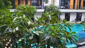Ein modernes Hotel mit Pool, üppiger Bepflanzung und einem Balkon mit Blick auf den Pool.