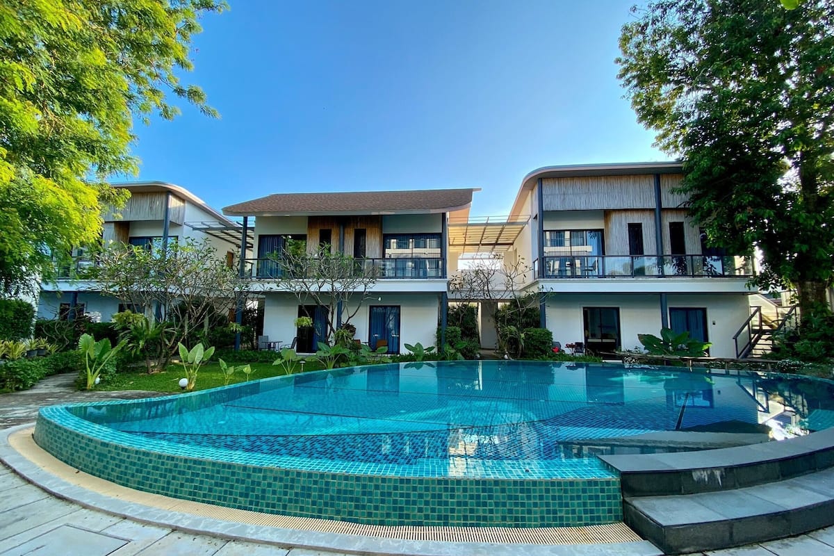 A modern hotel with a swimming pool, two-story buildings, and a garden.