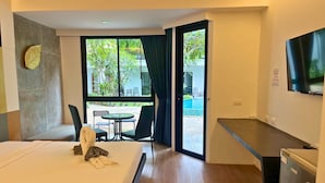 Ein Hotelzimmer mit Bett, Schreibtisch, Fernseher und Blick auf einen Swimmingpool.