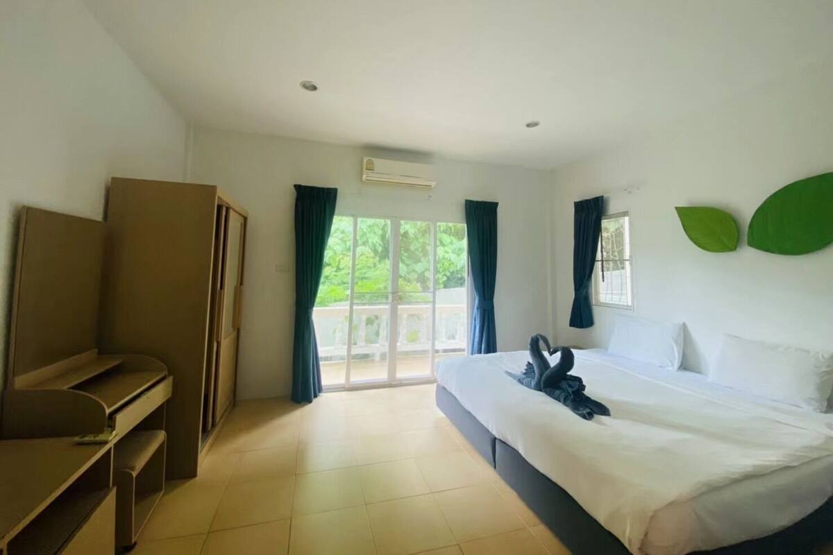A hotel room with a bed, a desk, a wardrobe, and a sliding glass door to the outside.