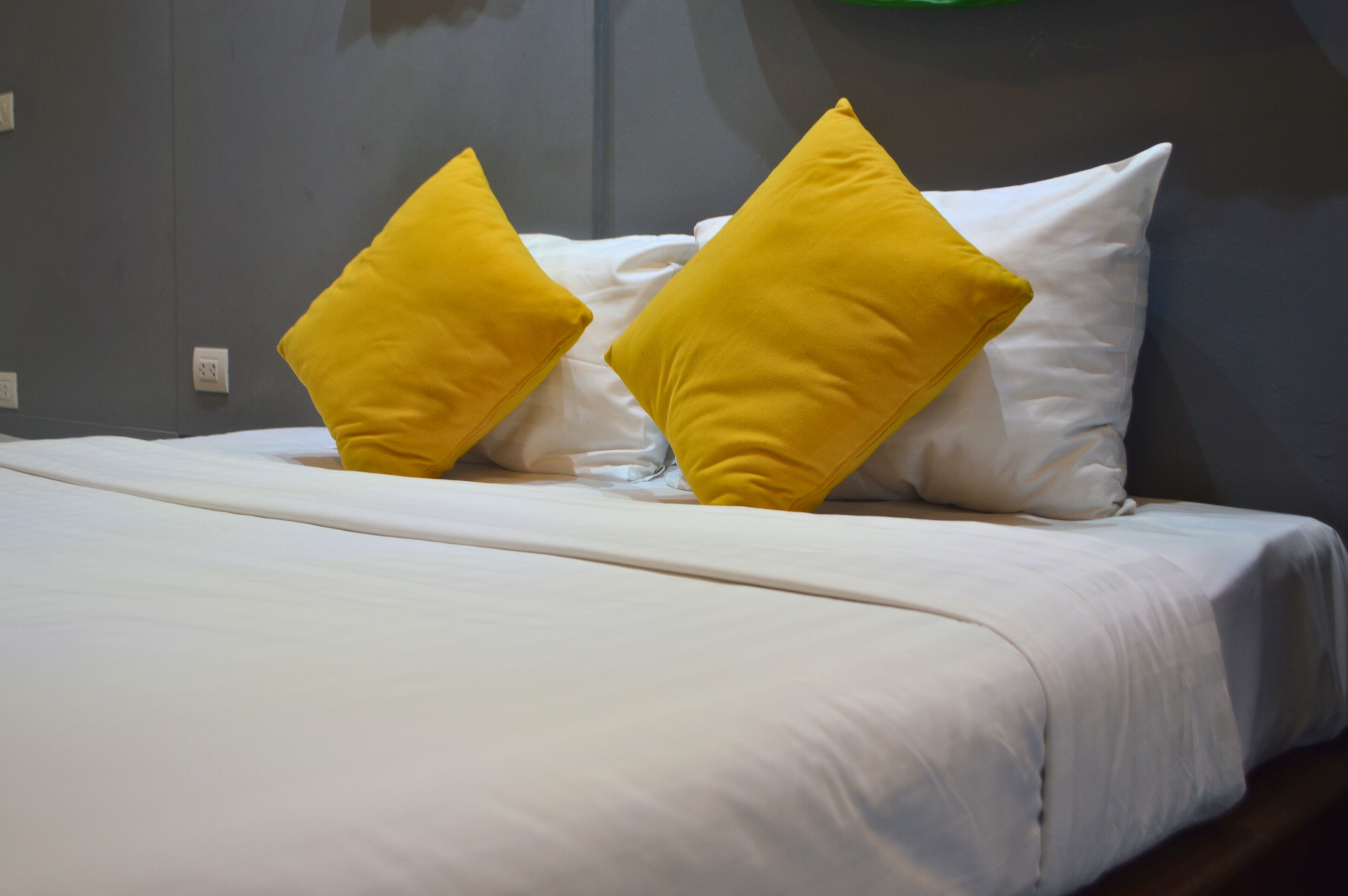 Una cama con ropa de cama blanca y dos almohadas amarillas.