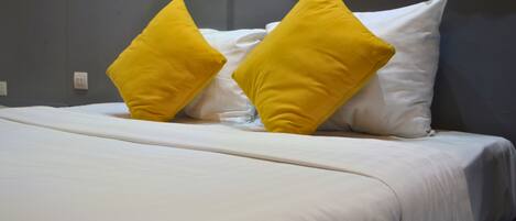 Una cama con ropa de cama blanca y dos almohadas amarillas.