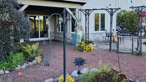 A two-story house with a balcony, outdoor seating area, and a garden with various plants and decorative elements. - 3 miles from Sunburst Ski Hill. Close to  great hikiing and snow mobile trails (Kewaskum)