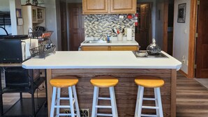 A modern kitchen with a central island, wooden cabinets, and a tiled backsplash. - 3 miles from Sunburst Ski Hill. Close to  great hikiing and snow mobile trails (Kewaskum)