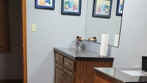 A kitchen with wooden cabinets, a granite countertop, and a black rug. - 3 miles from Sunburst Ski Hill. Close to  great hikiing and snow mobile trails (Kewaskum)