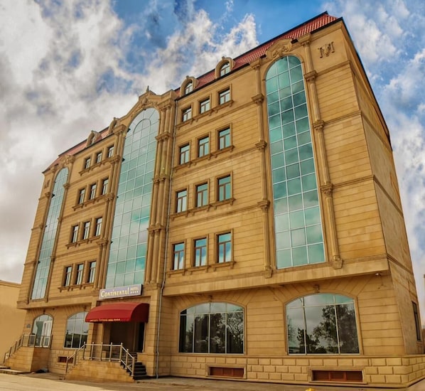 A historic hotel with large arched windows, a red awning, and a classic architectural style.