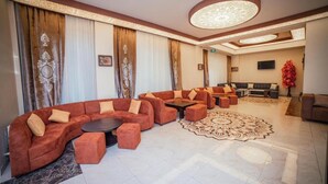 A modern hotel lobby with a curved sofa set, a round coffee table, and a patterned rug. - Continental Hotel Baku (Baku)