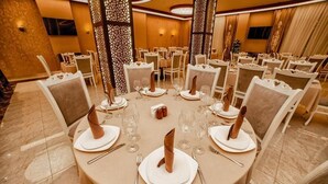 A banquet hall with round tables set for dining, each with white tablecloths, silverware, and folded napkins. - Continental Hotel Baku (Baku)