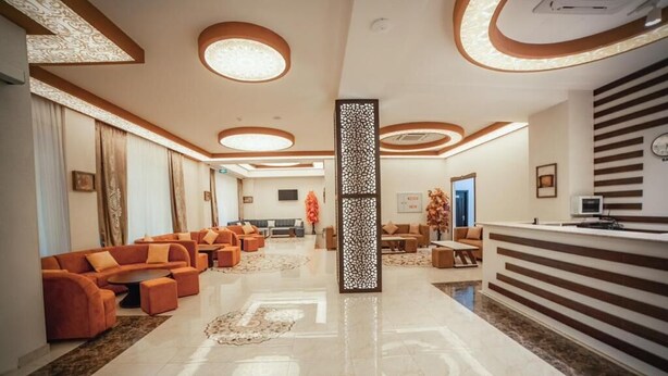 A spacious lobby with a reception desk, seating area with sofas, and a decorative partition. - Continental Hotel Baku (Baku)