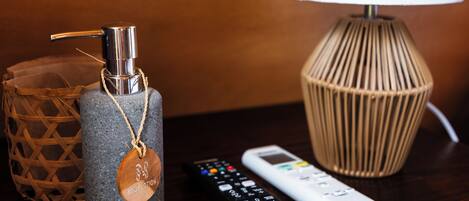 A remote control, a body lotion dispenser, and a lamp on a wooden surface.
