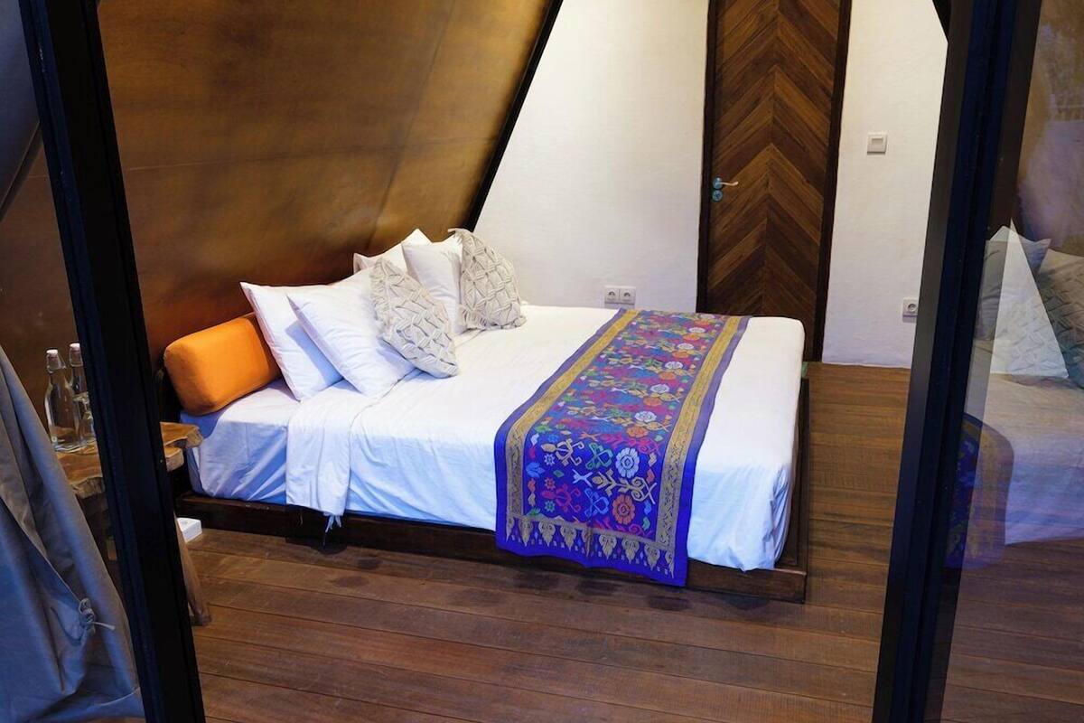 A bed with white linens, a colorful blanket, and several pillows.