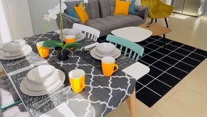 A dining area with a table set for four, a grey sofa, a yellow armchair, and a potted orchid. - Apartment on the beach, new (Bat Yam)