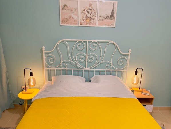 A bed with a white metal headboard, two bedside tables with lamps, and a yellow bedspread.