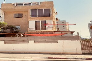 A multi-story building with a flat facade, balconies, and a gated entrance.