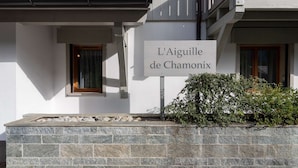A building with a stone wall and a sign reading "L'Aiguille de Chamonix".