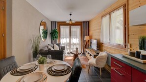 A cozy, well-lit room with a dining area, a sofa, and a kitchen.