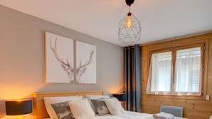 A neatly made bed with pillows and a blanket, a bedside lamp, and a fur rug on the floor.