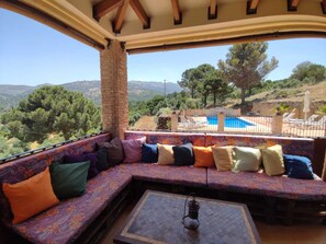 A cozy outdoor seating area with a view of a pool and mountains. - Stunning villa in Ronda with a private pool and barbecue. (Ronda)