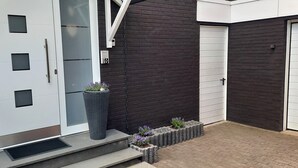 A modern building with a dark exterior, a white garage door, and a small entrance with steps leading up to a door.