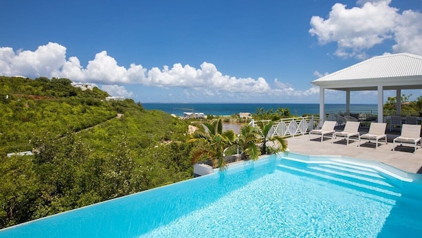 A rooftop infinity pool with a view of the ocean, lounge chairs, and a covered seating area. - Villa Angelsmart – Contemporary Sea View Villa Overlooking Red Bay, St. Maarten (Phillsburg)