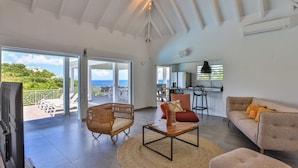 A spacious living area with a large window, a dining area, and a kitchen. - Villa Angelsmart – Contemporary Sea View Villa Overlooking Red Bay, St. Maarten (Phillsburg)