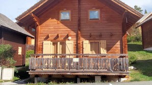 A wooden cabin with a balcony, two windows, and a small porch. - Chalet in La Joue du Loup, sleeps 6, terrace, parking (La Joue du Loup)