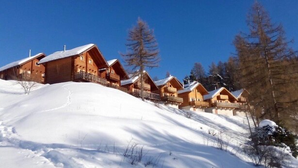 A row of wooden cabins with balconies, set against a snowy landscape and clear blue sky. - Chalet in La Joue du Loup, sleeps 6, terrace, parking (La Joue du Loup)
