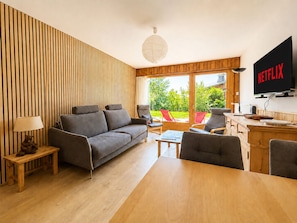A modern living room with a sofa, chairs, a coffee table, and a TV displaying 'NETFLIX'.