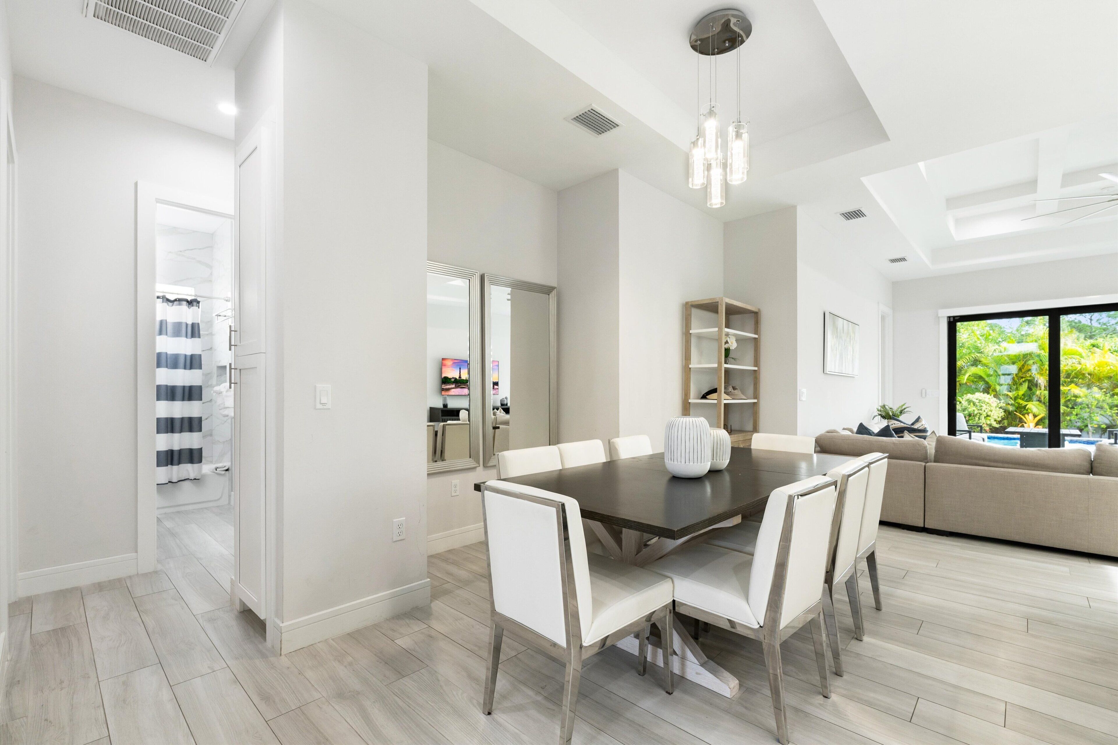 Un espace repas moderne avec une grande table, des chaises blanches et un lustre.